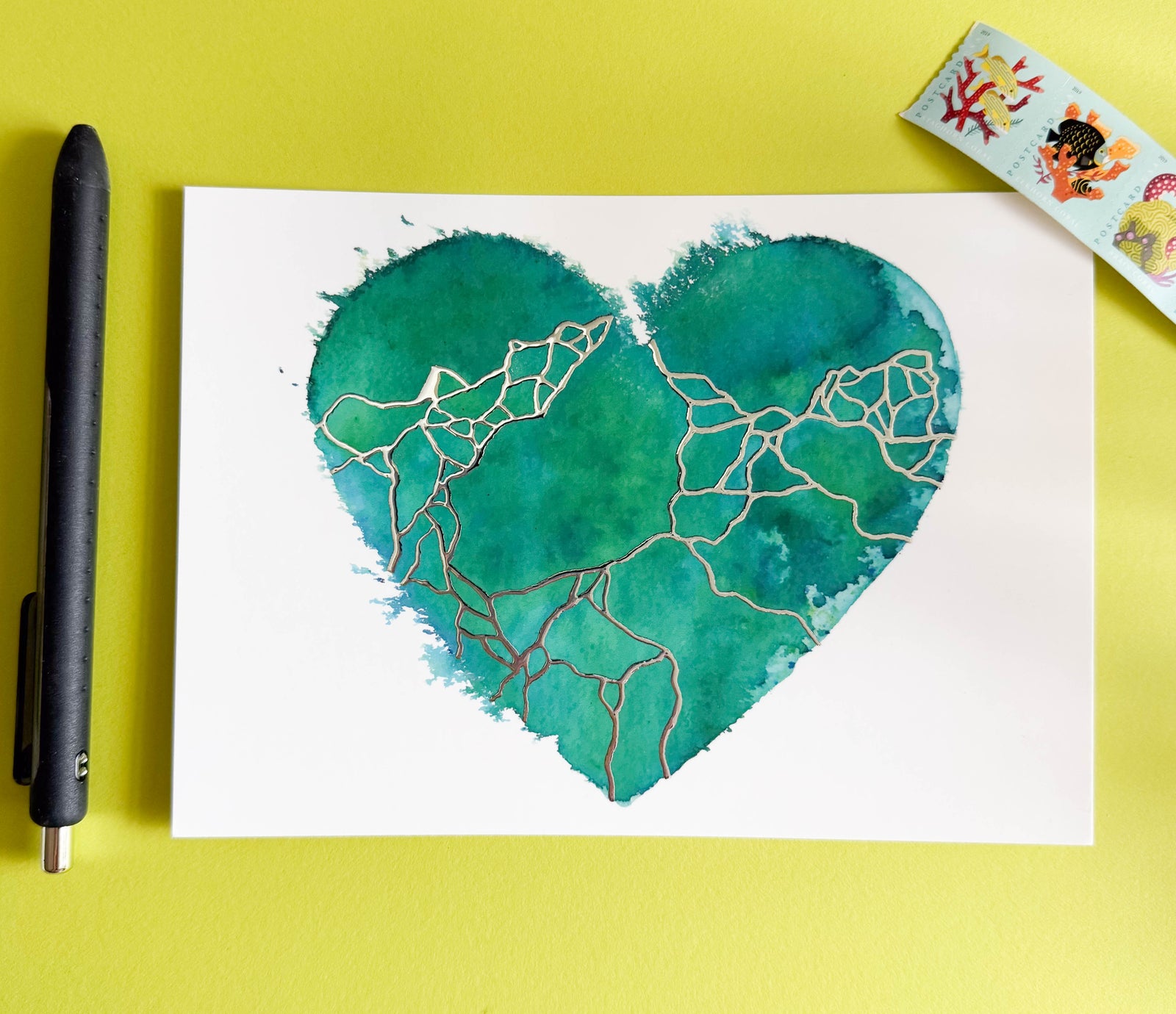 Heart-shaped artwork with green watercolor and gold lines on a yellow background