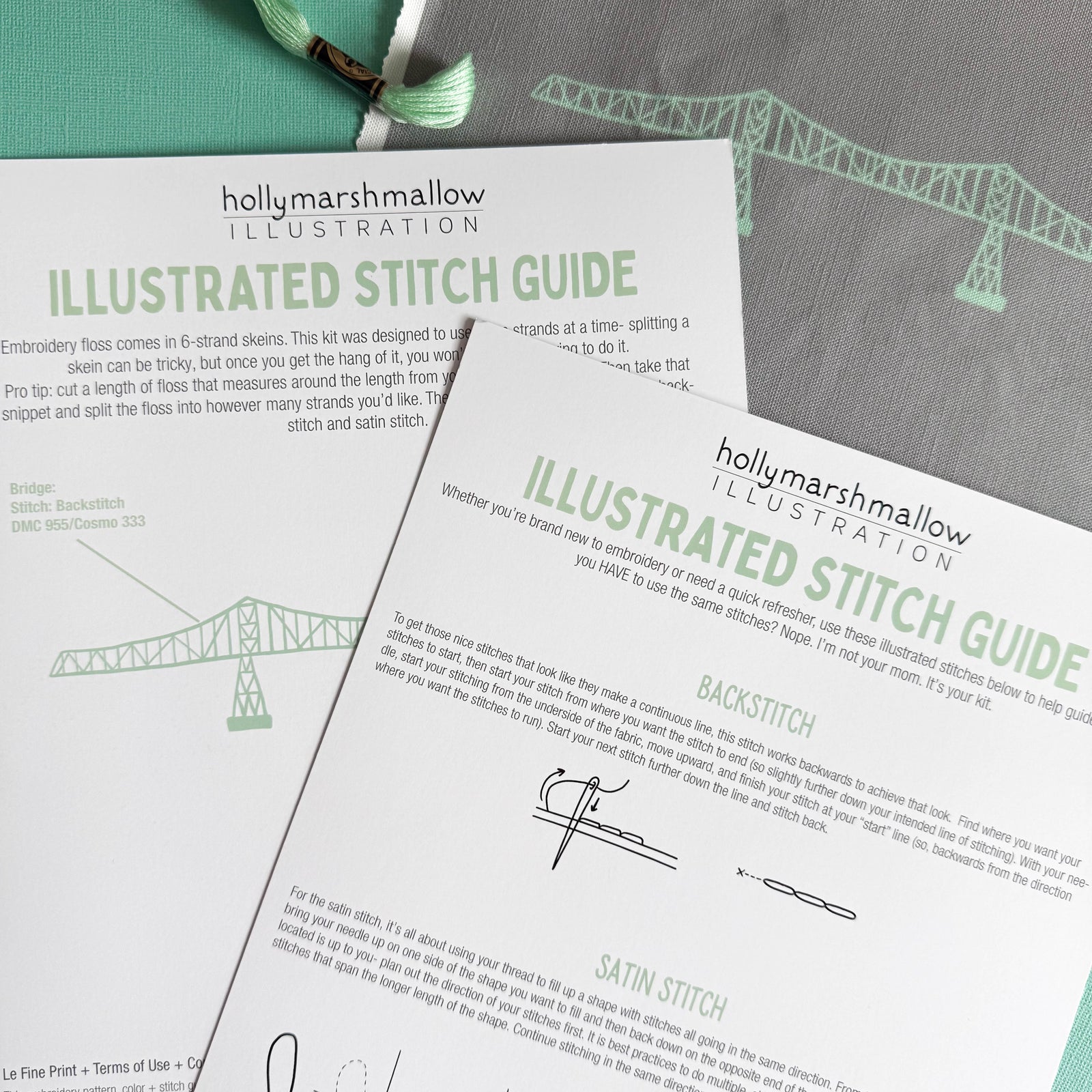 Flatlay of the illustrated stitch guide that comes with the kit. The preprinted fabric is laying under them to the upper right, and the skein of embroidery floss peeks out in the top left corner.