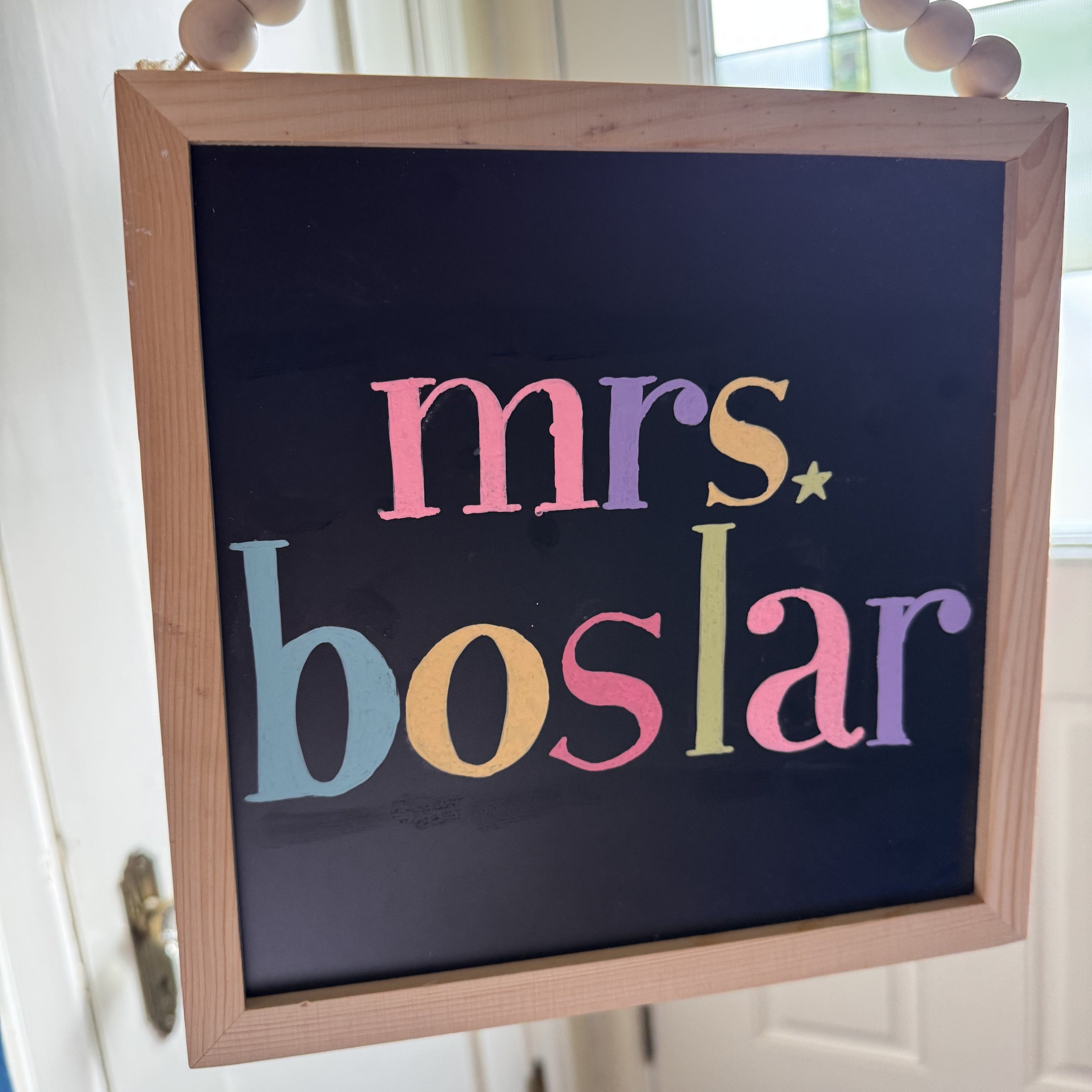 Decorative sign with 'mrs. boslar' text in colorful letters on a black background.