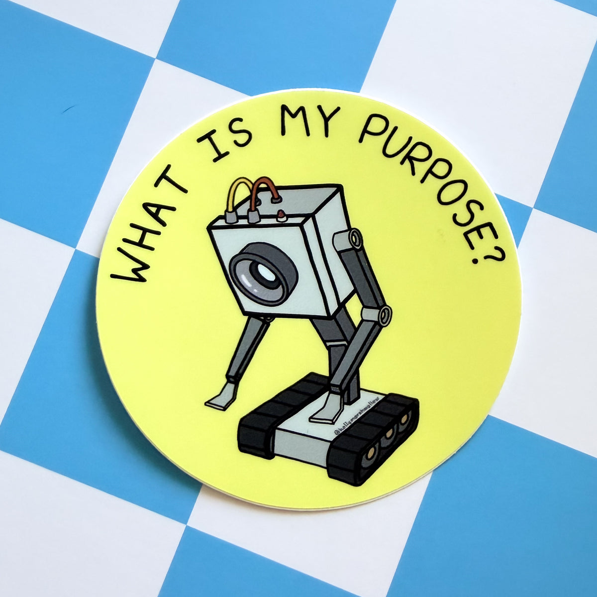 Yellow circle sticker with the Butter Robot from Rick + Morty in the center with hand-lettered text that reads What is My Purpose? on a blue and white checkered background