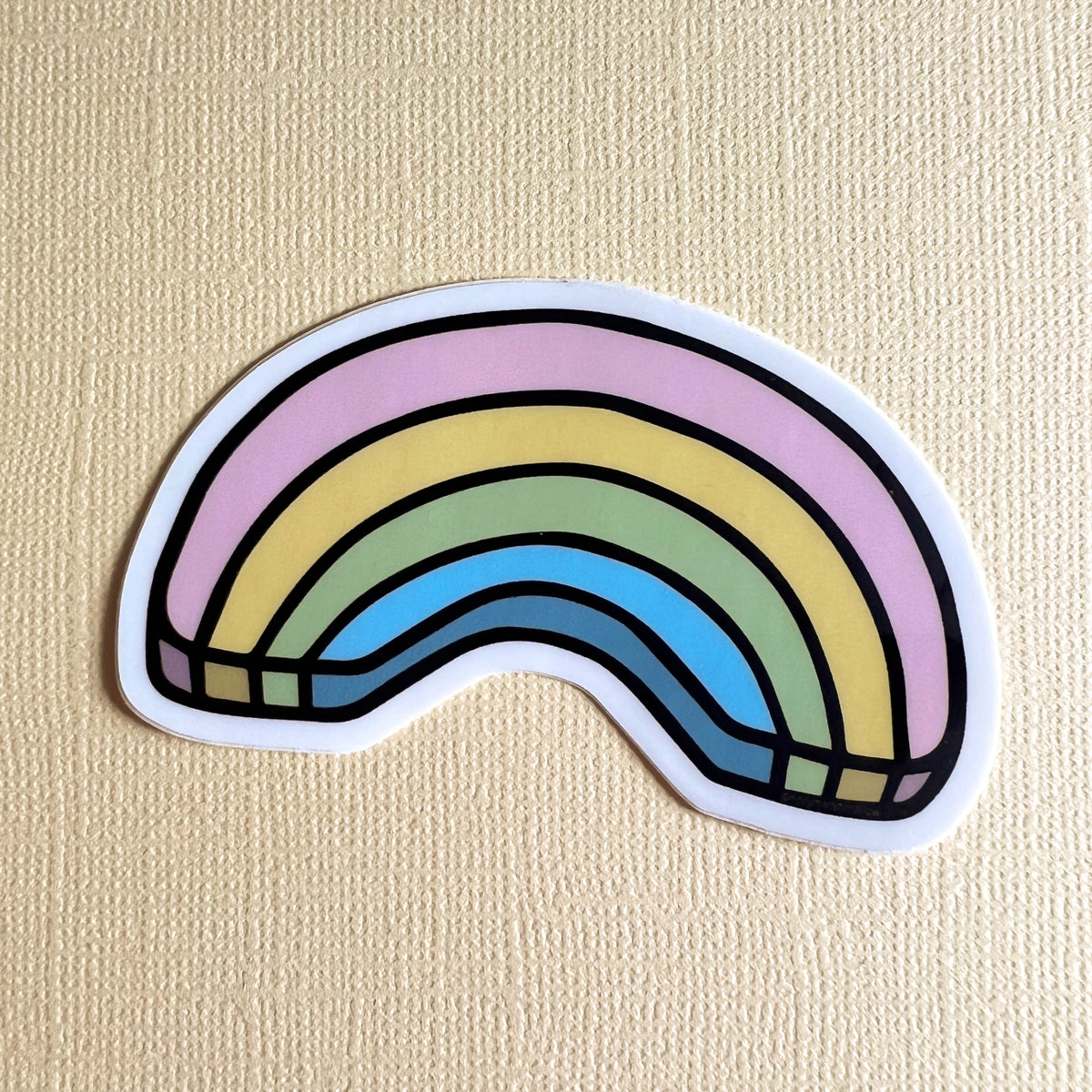 Pastel rainbow sticker on a light yellow background