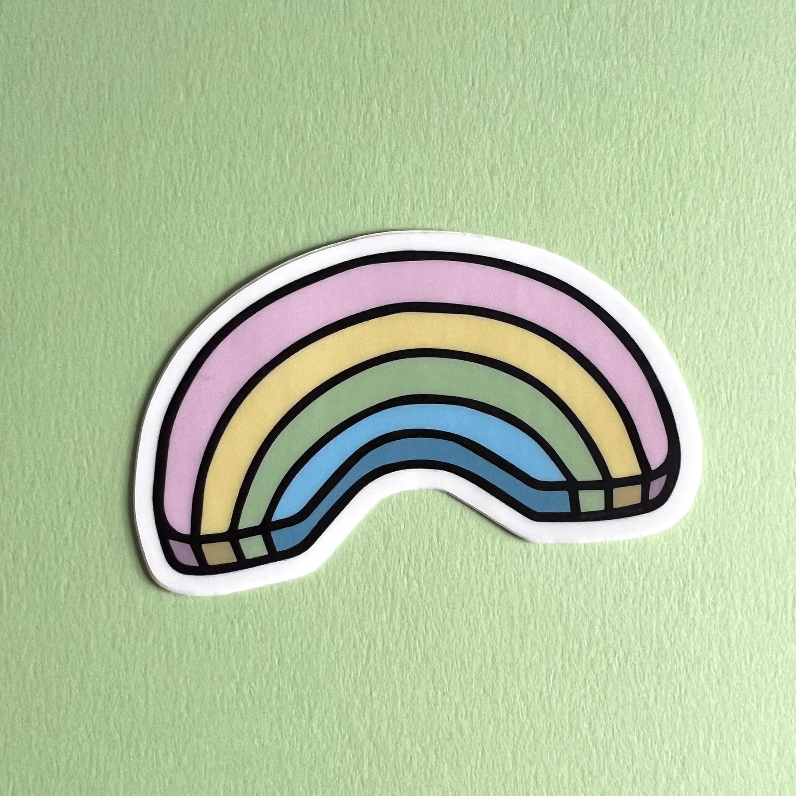 Pastel rainbow sticker on a light green background