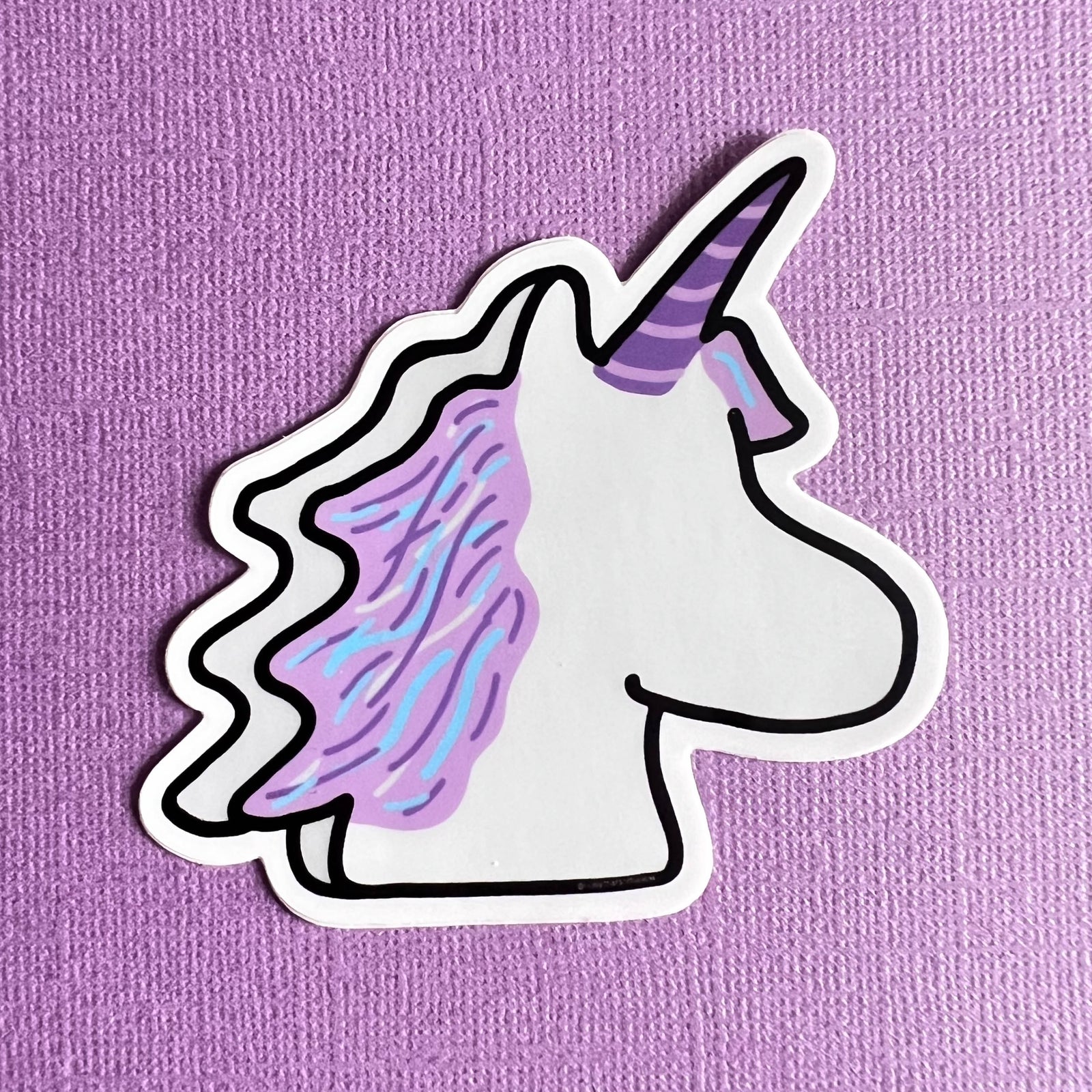 Marshmallow Unicorn sticker with a purple horn and mane on a purple background