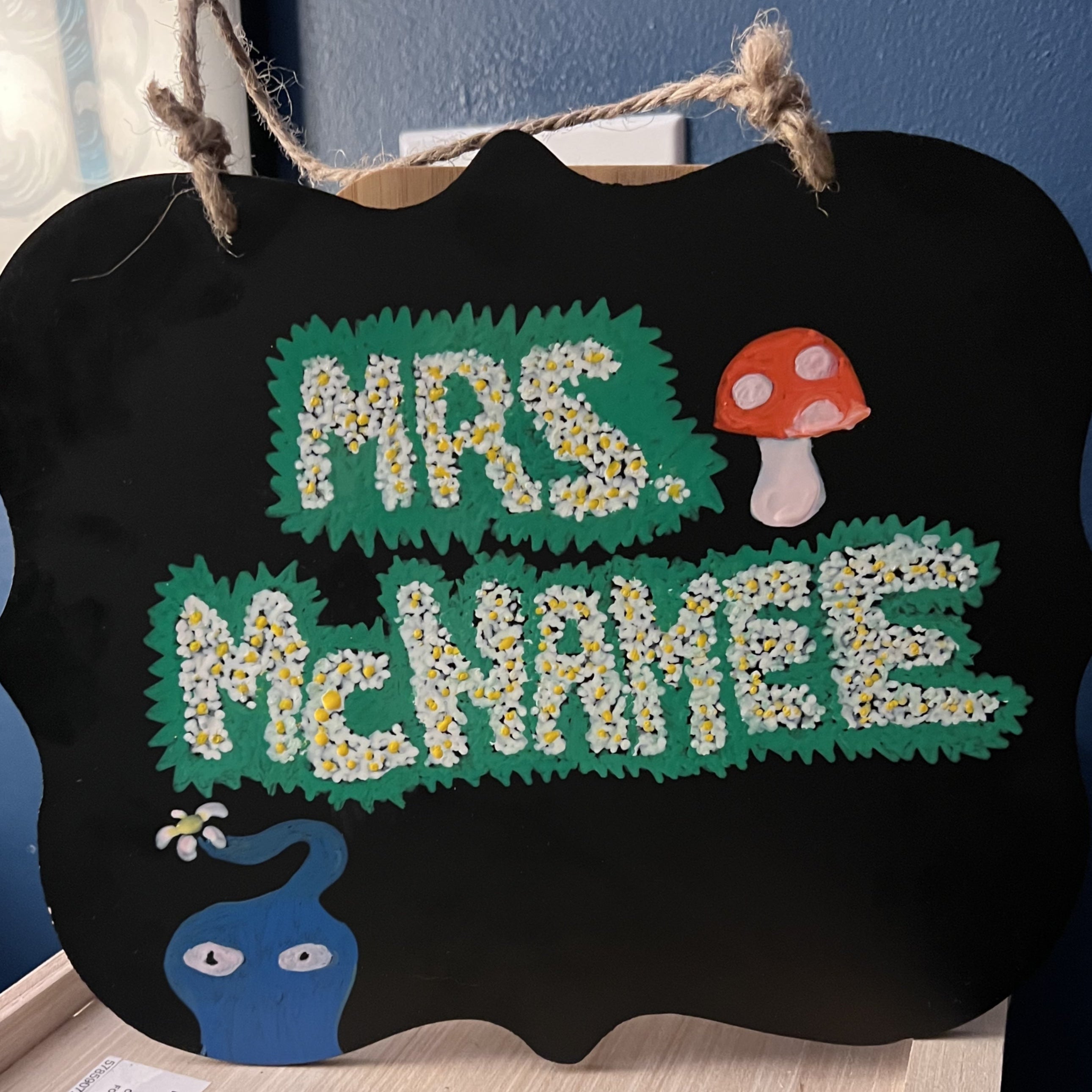 Decorative sign with 'Mrs. McNamee' Pikmin-inspired hand lettering on a black background
