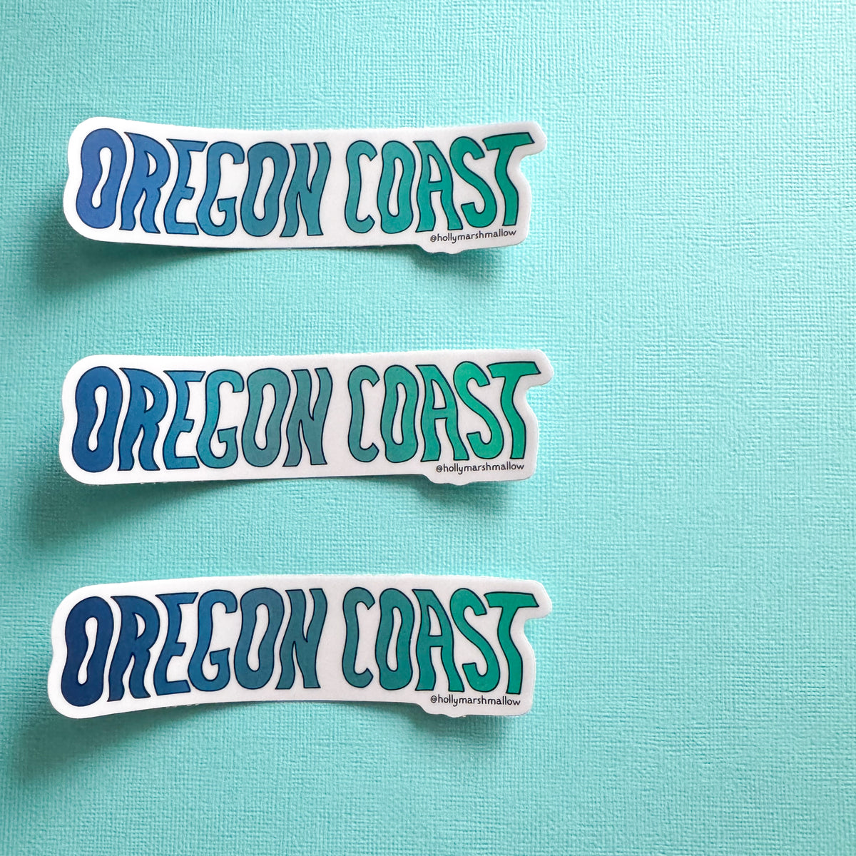 Three 'OREGON COAST' stickers on a teal background