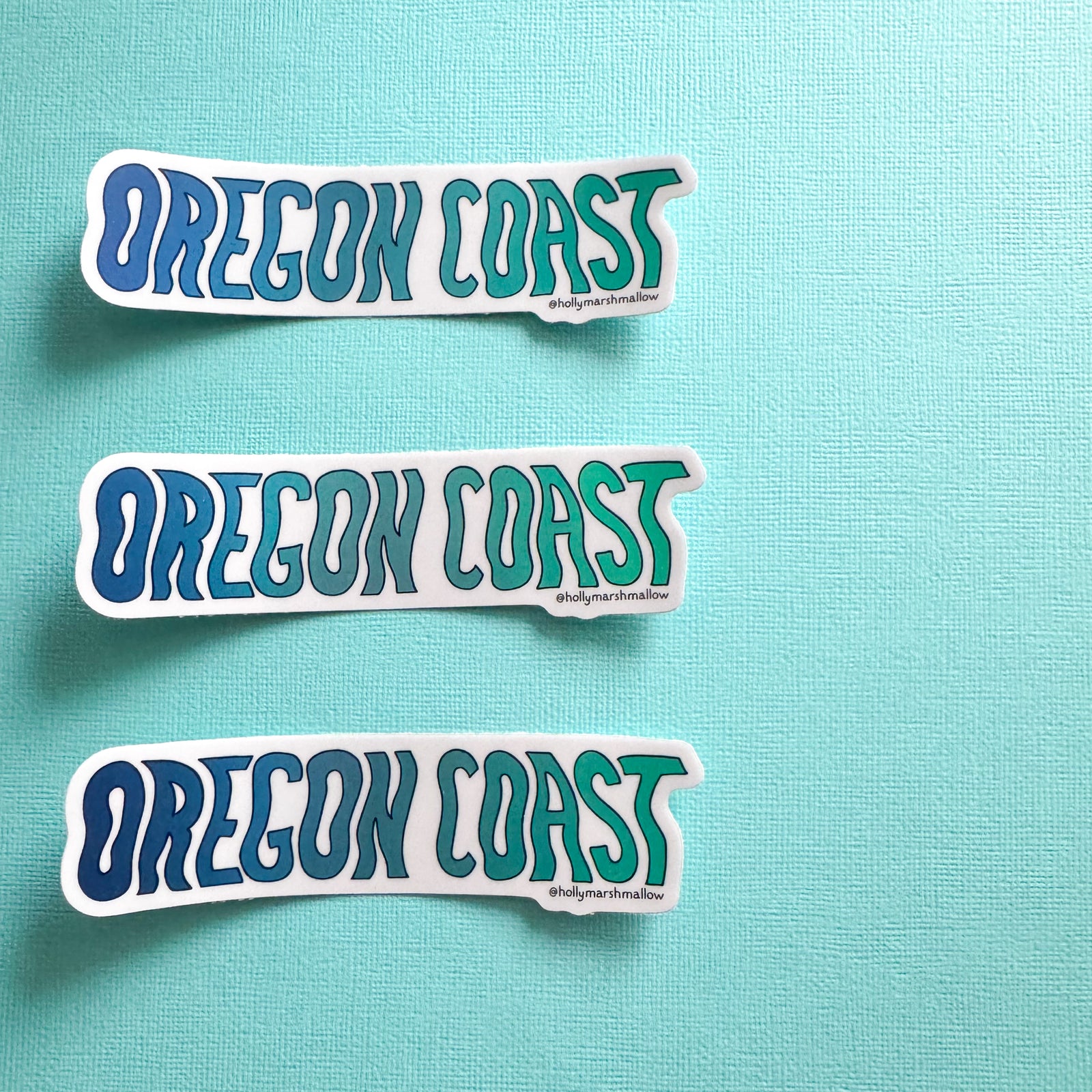 Three 'OREGON COAST' stickers on a teal background