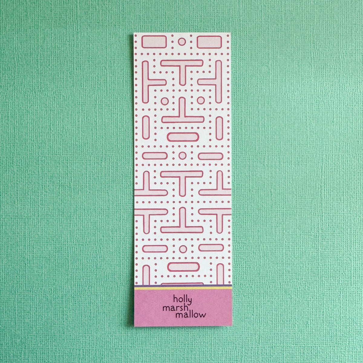 Rectangular pink arcade maze pattern on back of bookmark on a green background