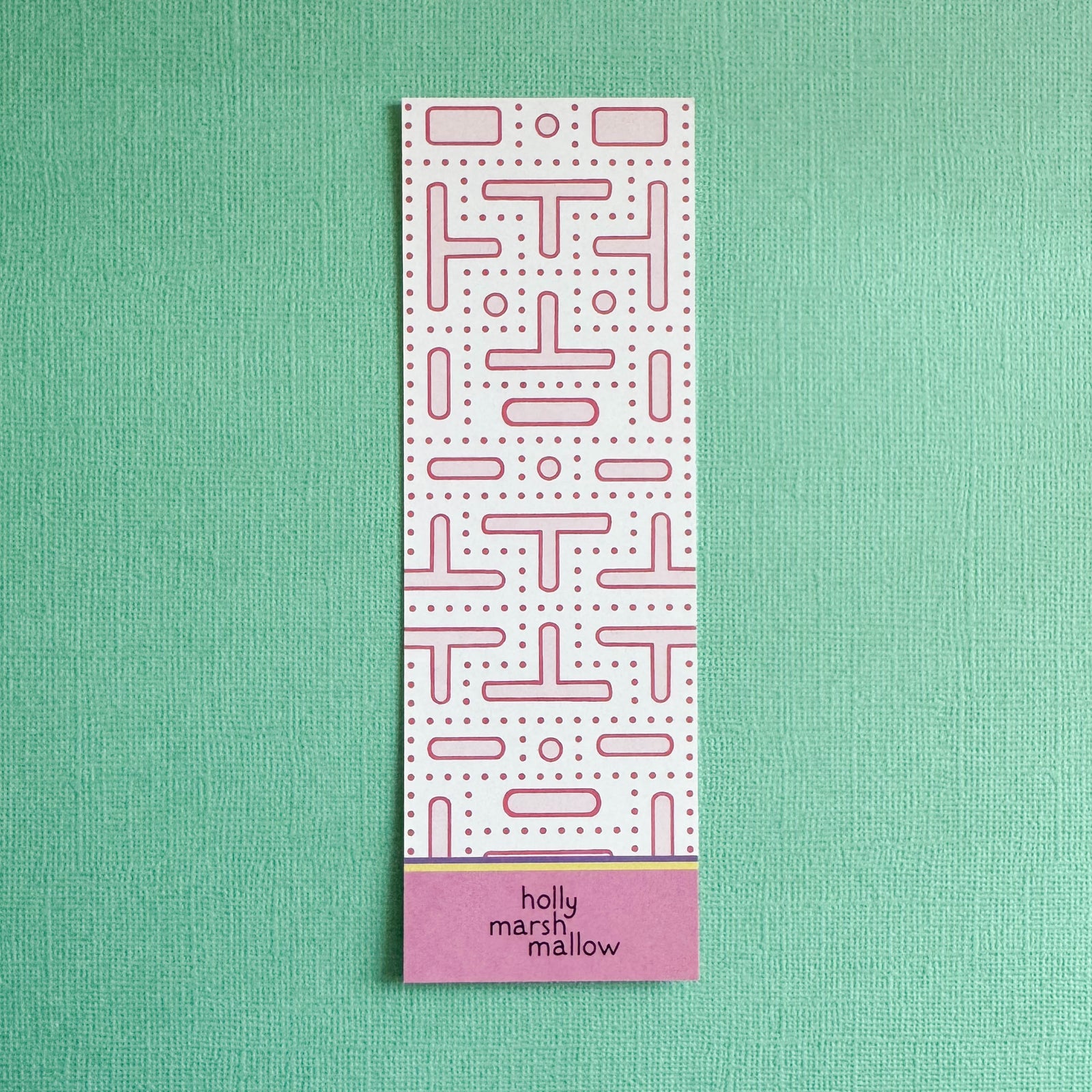 Rectangular pink arcade maze pattern on back of bookmark on a green background