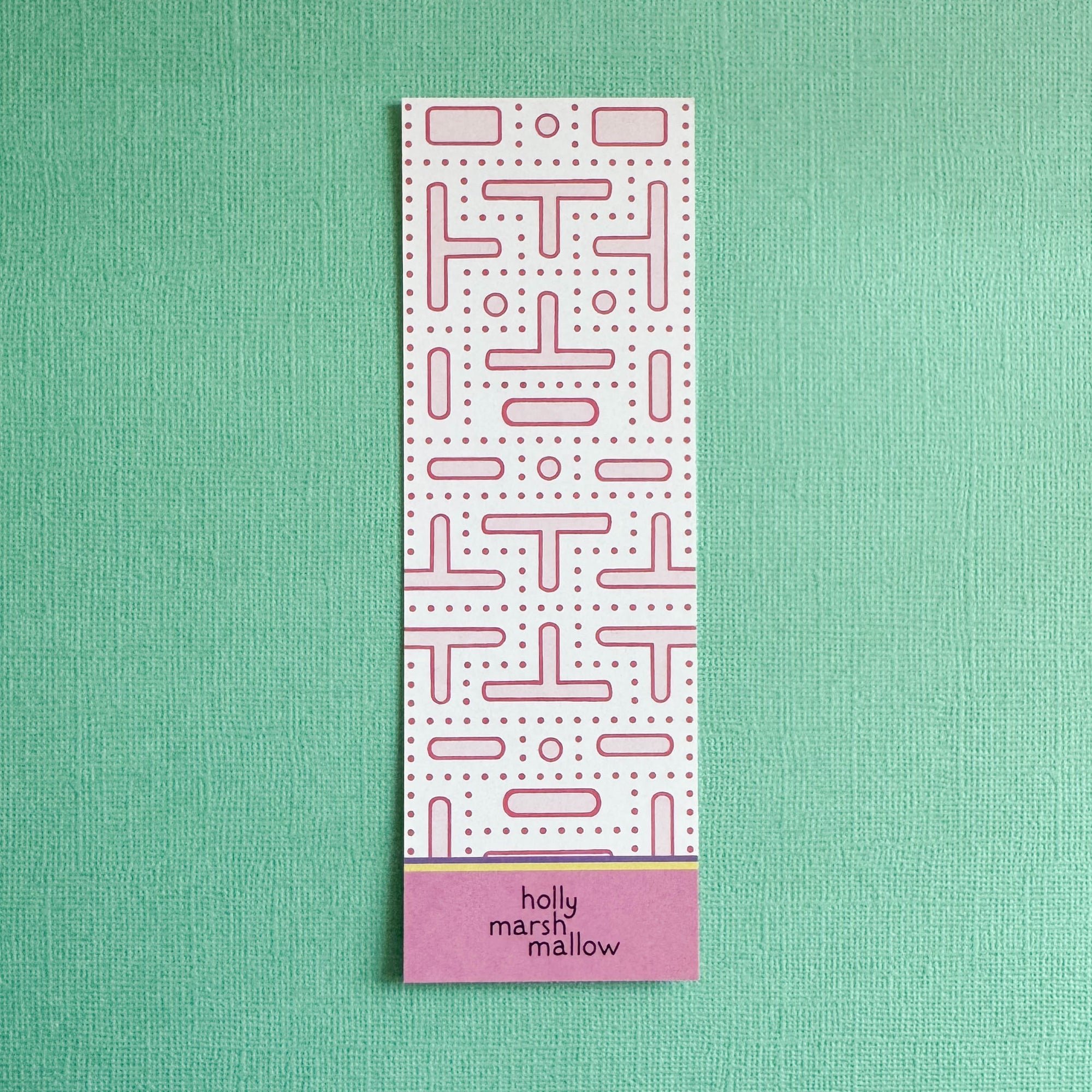 Rectangular pink arcade maze pattern on back of bookmark on a green background