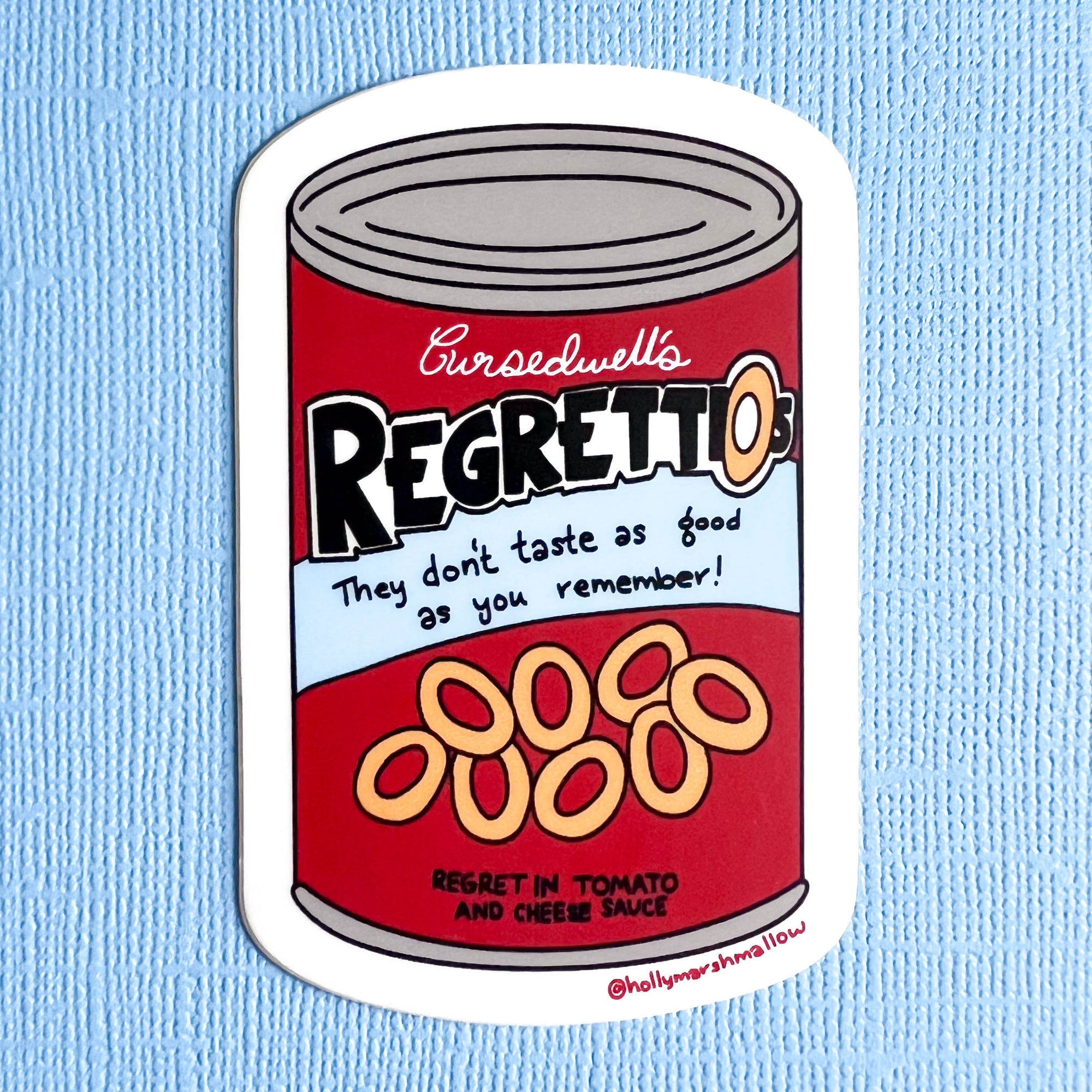 Sticker of a can labeled 'Cursedwell's Regretti-os' on a blue background