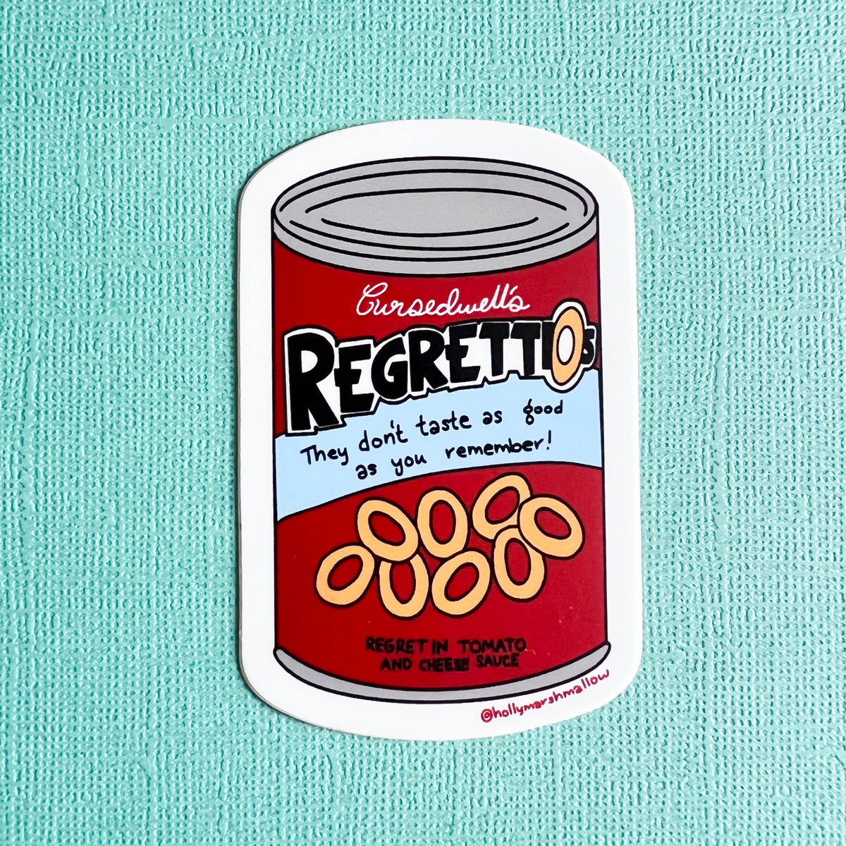 Sticker of a can labeled 'Cursedwell's Regrettios' on a light teal background