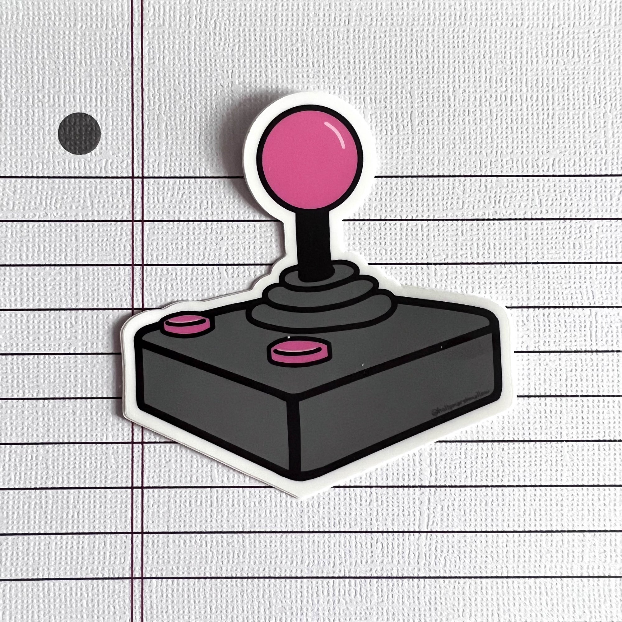 Joystick sticker with pink top and buttons on a lined paper background