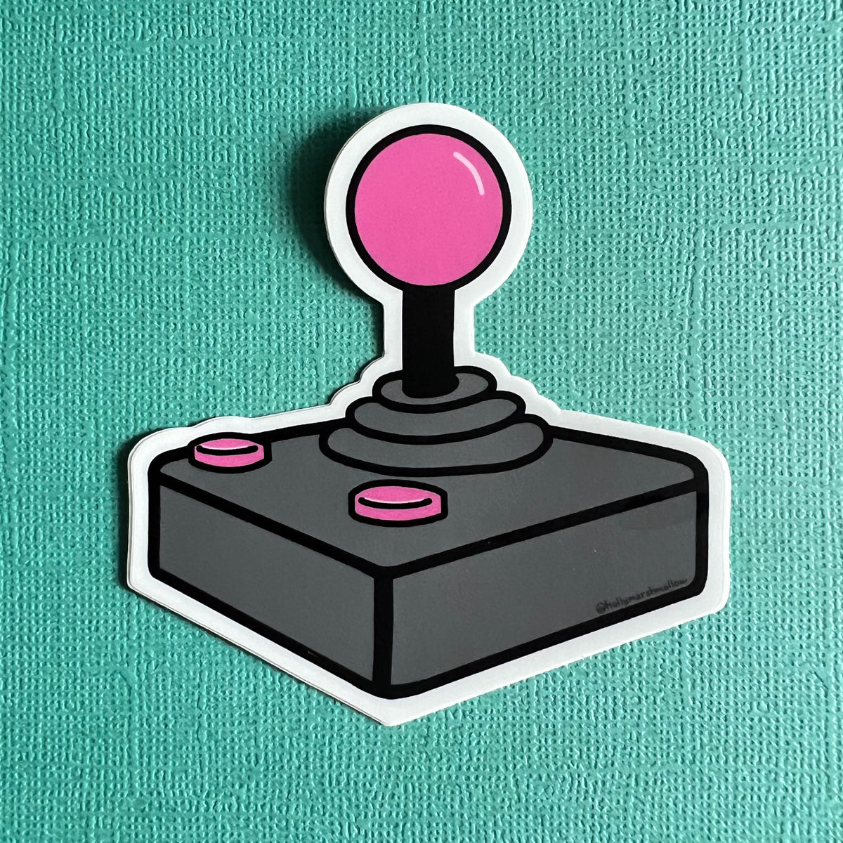 Joystick sticker with pink ball and buttons on a teal background