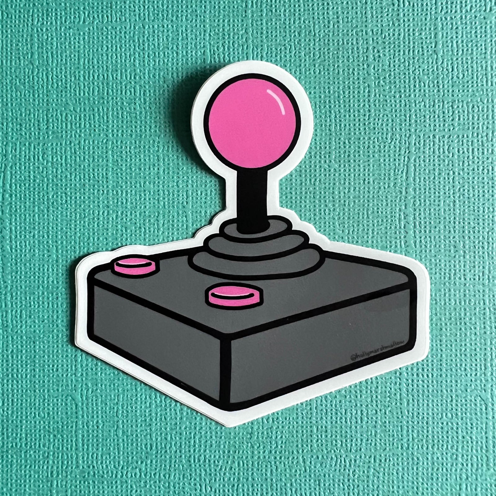 Joystick sticker with pink ball and buttons on a teal background