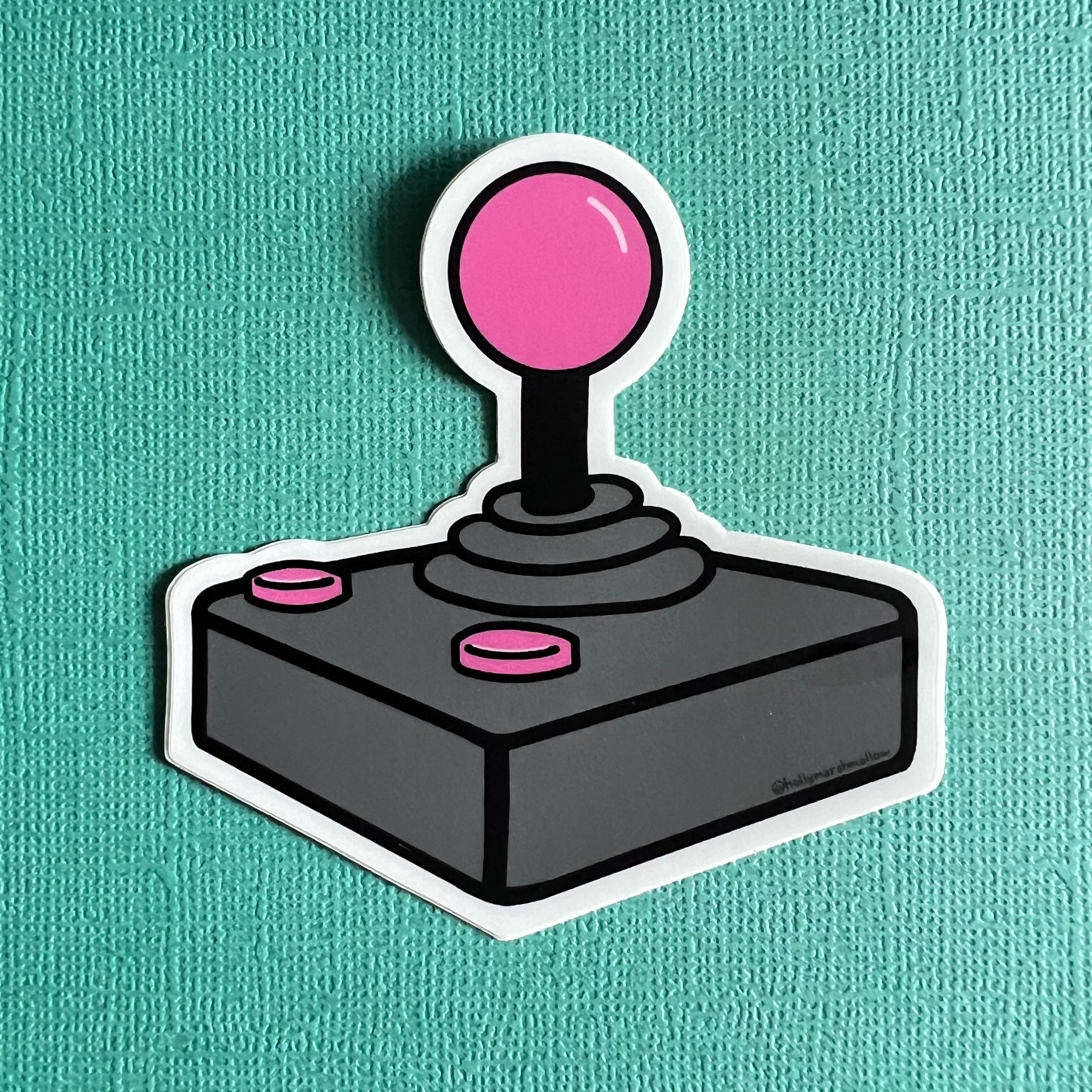 Joystick sticker with pink ball and buttons on a teal background