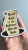 video of a hand holding a sticker of an illustrated parchment scroll in a hole with the hand lettered words Don't Fall in the Infinite Scroll Hole