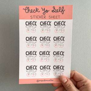 Hand holding sticker sheet with 12 Check Yer Bewbs stickers on a grey background