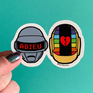 Hand holding an illustrated Daft Punk die cut sticker on a teal background