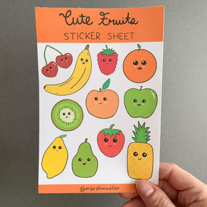 Hand holding Cute Fruits sticker sheet on a grey background