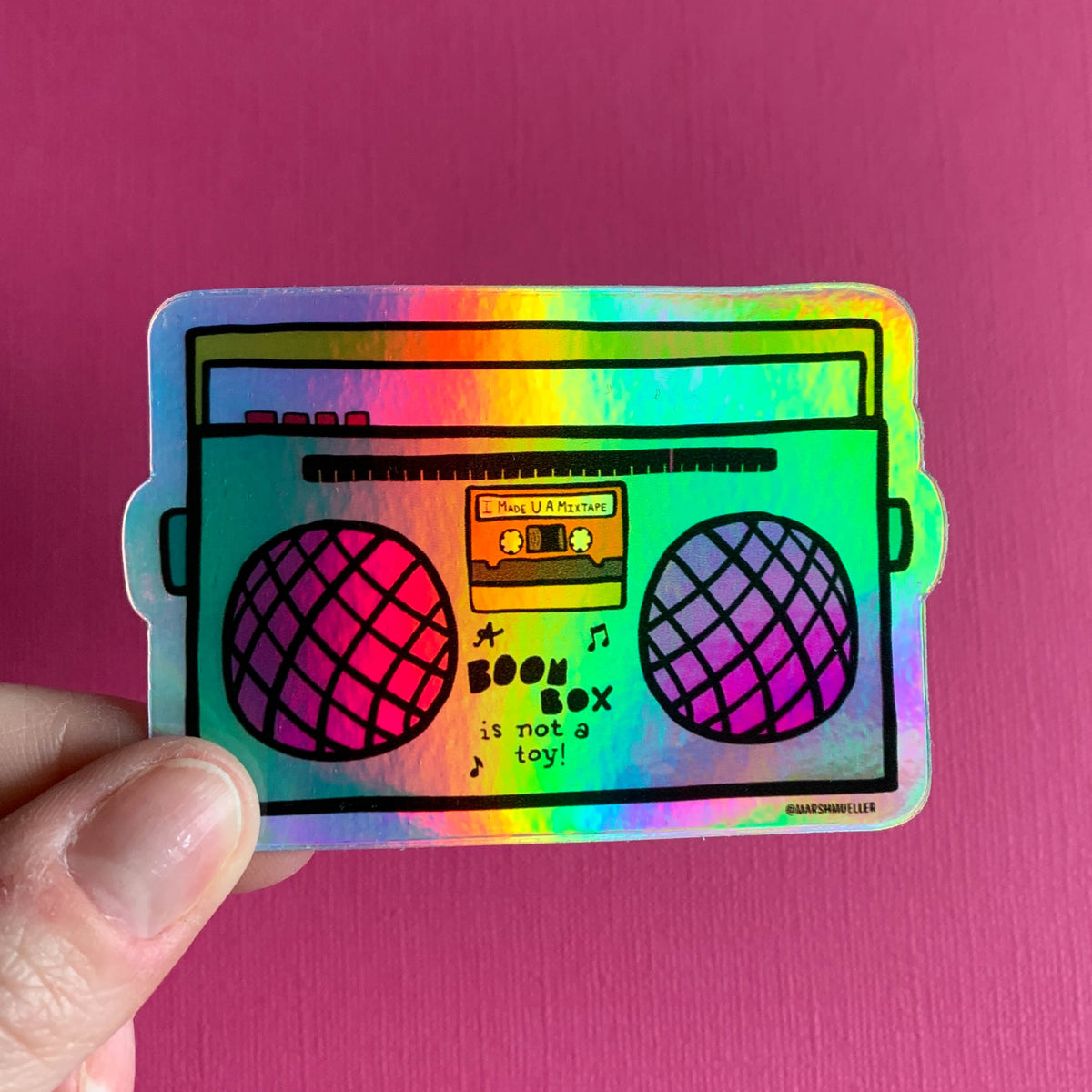 hand holding a holographic die cut sticker of a boom box illustration on a pink background