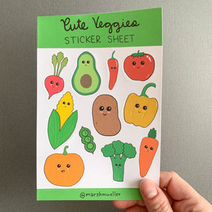 Hand holding Cute Veggies sticker sheet on a grey background