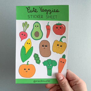 Hand holding Cute Veggies sticker sheet on a grey background